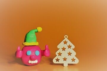 A figure of a joyful virus in a festive hat. There is a Christmas tree nearby. A festive event.