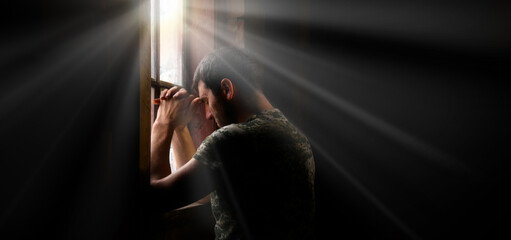 Sad soldier praying at the window