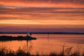Fototapeta na wymiar Sunset in Sweden at the harbor of lake Vaettern. Lighthouse in the background