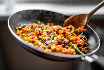 cooking tasty vegetable mix with corn, pea, beans in pan on kitchen