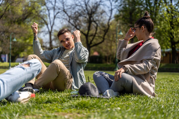 Group of young people having fun in park, sitting on the grass