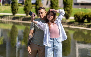 Young couple using mobile phone taking a selfie in the park