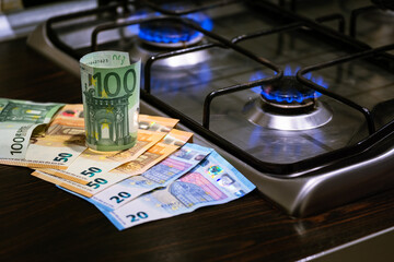 Euro banknotes next to gas cooking stove in dark light kitchen  - Concept of increasing energy costs due to current geopolitical events