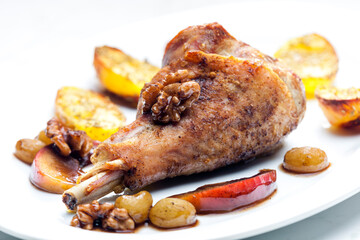 poultry leg baked with fruit and walnuts served with fried potatoes