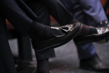 A sit man with moccasin cross his legs during a meeting