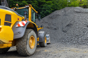 yellow digger with grey gravel for construction of the road
