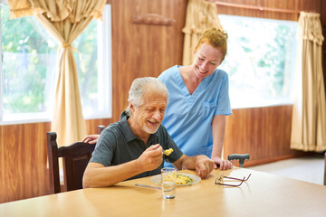 Altenpflegerin betreut Senior beim Mittagessen