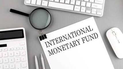 INTERNATIONAL MONETARY FUND written on paper with office tools and keyboard on the grey background