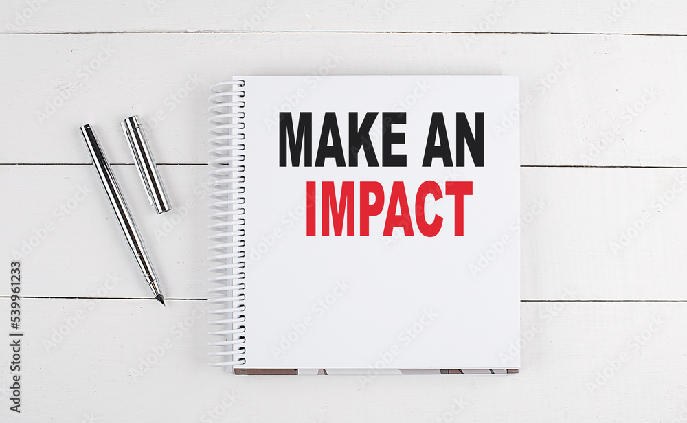 Poster make an impact text written on notebook on the wooden background