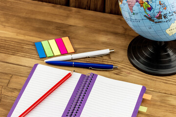 Education concept. Top view of blank notebook with school and office supplies on wooden background