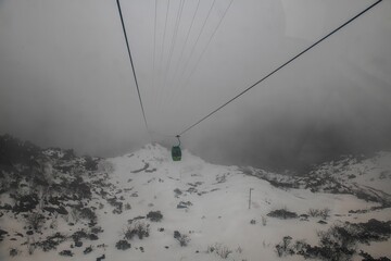 View of snow-covered mountain slope in dense fog with Tsongo passenger ropeway in Gangtok, Sikkim
