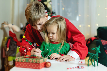 Merry Christmas and happy holidays! Happy Little  girl dressed in red-green pajamas and his big...