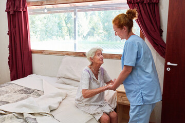Altenpflegerin hilft Seniorin beim Aufstehen
