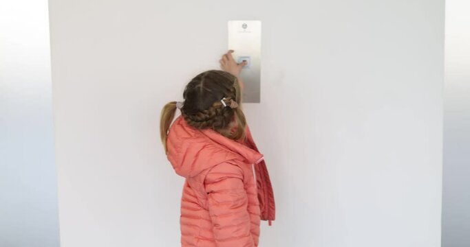 Cute little girl pressing elevator button with her finger. Child reaching to push a button in a lift.