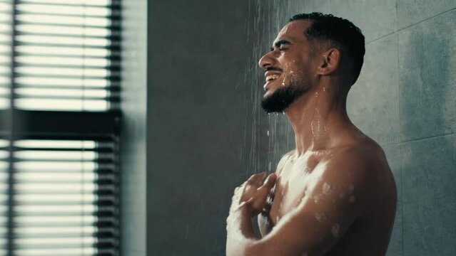 Singing dancing man in bath happy carefree Indian Latina Hispanic guy naked sexy male sing song listening music in shower dance funny move in bathroom at home hotel morning hygiene cleaning procedure