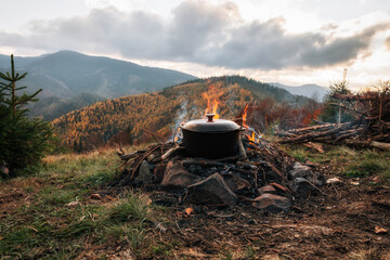 Bowler cooking food bonfire cauldron camp fire, pot. Hiking pot in the bonfire. Traveling in the...