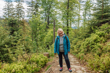 Fototapeta premium Man and 50s woman hiking on wet rocks at mountain. Babia Gora Poland