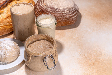 Healthy lifestyle, gluten free fermenting diet. Homemade sourdough. Active bubbly rye, wheat, oat sourdough with different flour and fermentation methods, in glass jars, with raw dough and baked bread