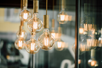 goldene Pendelleuchten mit Warmweissem Licht vor einer Glasscheibe