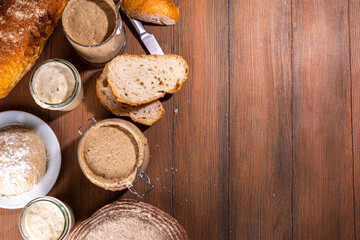 Healthy lifestyle, gluten free fermenting diet. Homemade sourdough. Active bubbly rye, wheat, oat sourdough with different flour and fermentation methods, in glass jars, with raw dough and baked bread