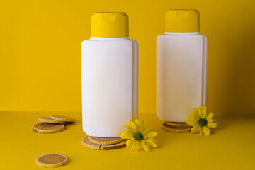 cosmetic products with chamomile flowers on yellow background