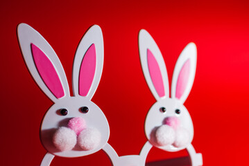 Fototapeta premium Two Toy Rabbit Bunny symbol of new year 2023 on red background.Christmas or New Year concept.Copy space.