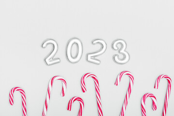 The inscription 2023 and red candy canes on a gray background. Christmas and New Year concept. Copy space.