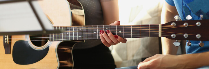 Female teacher explain notes to client on guitar instrument, music class at home