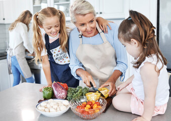 Obraz na płótnie Canvas Grandmother, children and cooking in the kitchen together with vegetables in the family home. Cutting, food and elderly woman in retirement teaching young girl kids to cook meal for lunch or dinner.