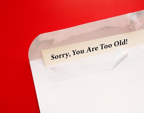 Torn envelope on red background with message SORRY, YOU ARE TOO OLD - age is used to categorize and divide people that lead to harm, disadvantage, and injustice, stereotypes prejudice discrimination 
