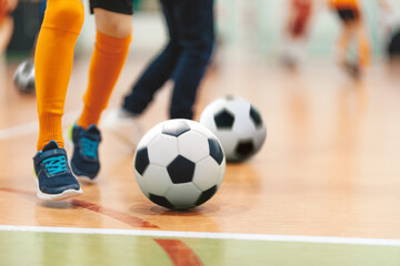 Futsal Soccer Ball on Indoor Training Pitch. Young Players On Sports Practice Running Balls in...
