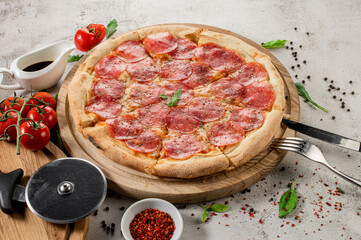 Fresh pizza with meat and ham on the concrete background