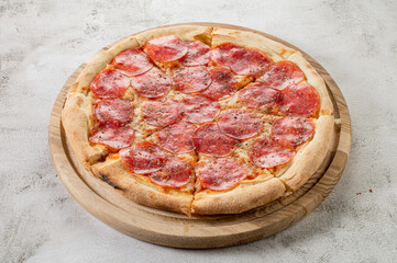 Fresh pizza with meat and ham on the concrete background