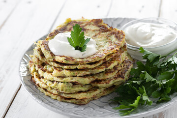Zucchini fritters with yogurt sauce on white wooden table