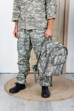 Partial View Of Military Man In Uniform And Boots Standing With Backpack Near Entrance Door At Home