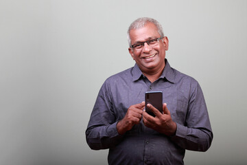Portrait of a smiling man of Indian ethnicity holding a mobile phone