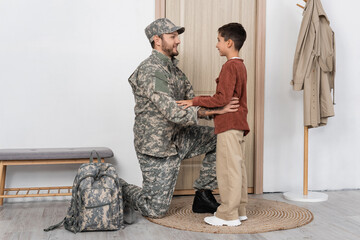 father in camouflage looking at happy son meeting him at home