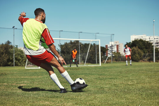 Soccer, sports and men on a field during a game, training or exercise together. Athlete kicking a football during a professional competition, event or sport with team in a park for fitness in summer - Powered by Adobe