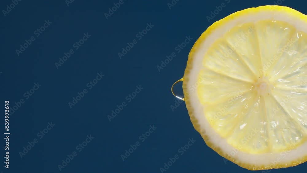 Poster Vertical of Slow Motion Macro Shot of  Water drop from Lemon Slice on blue-black Background