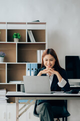 Asian Business woman using calculator and laptop for doing math finance on an office desk, tax, report, accounting, statistics, and analytical research concept