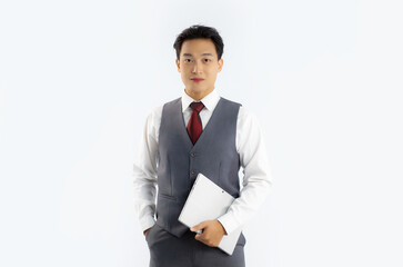 Portrait of asian businessman in vest suit holding tablet looking camera on white background.
