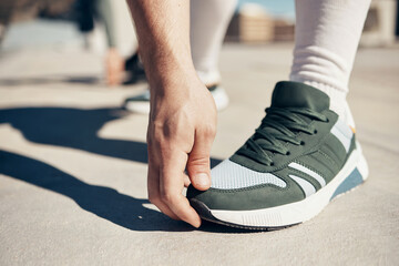 Shoes, hand and stretching with a sports man touching his toes during an exercise or fitness warmup in the city. Health, training and workout with a male athlete getting ready for competition closeup