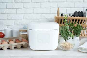 Fototapeta na wymiar Electric rice cooker on wooden counter-top in the kitchen