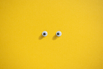 Ten plastic eyes on a yellow background. Idea for Halloween. Holiday postcard. Children's craft. Yellow background. Lots of eyes. Selective focus.