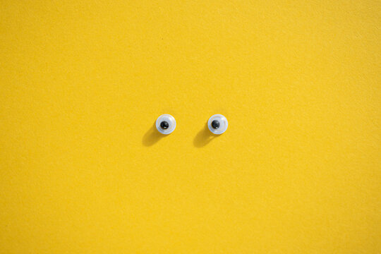 Ten plastic eyes on a yellow background. Idea for Halloween. Holiday postcard. Children's craft. Yellow background. Lots of eyes. Selective focus.