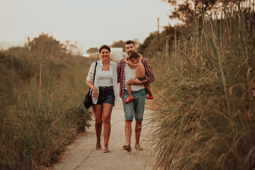 The family walks an idyllic path surrounded by tall grass. Selective focus 