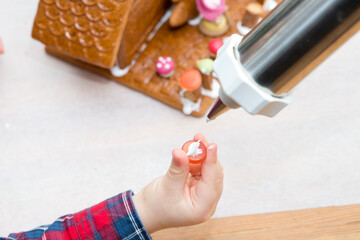 Two brothers making Christmas Gingerbread house. Adding decorations and other accents. Festive spirit, rapprochement, cohesion, reconciliation. Creating family traditions.