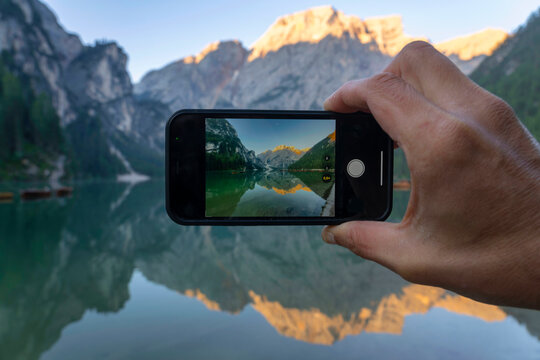 Phone screen with a picture of Lake Braies at sunrise, Dolomites, Alto Adige, Italy