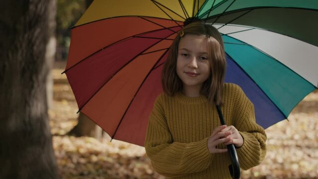 Portrait of caucasian girl in the park holding a colorful umbrella. Shot with RED helium camera in 8K.  