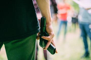 A firearm in a person's hand. Close-up. The man hides a gun in his hand